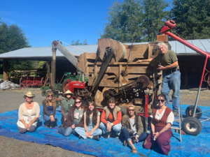 A group of eight individuals sitting in front of farming machinery